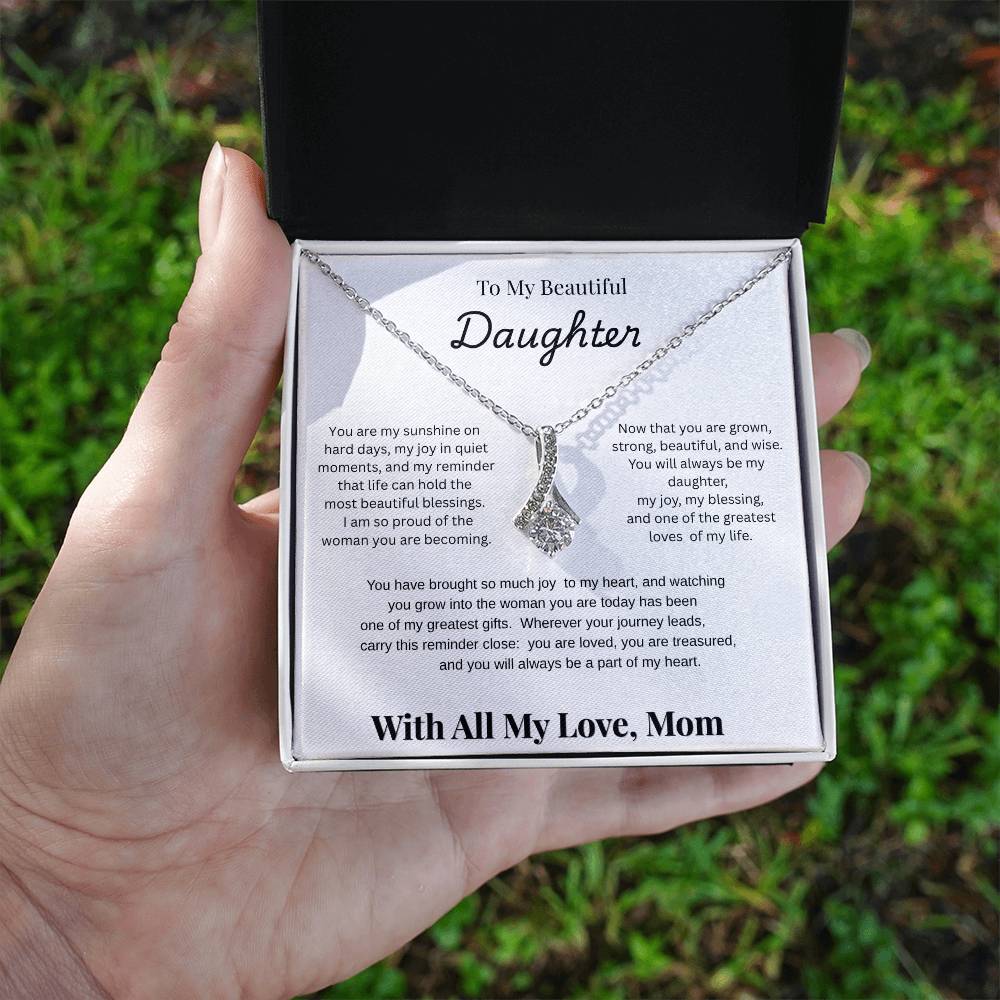 Hand holding 14k white gold-finish Alluring Beauty Necklace in standard gift box outdoors
