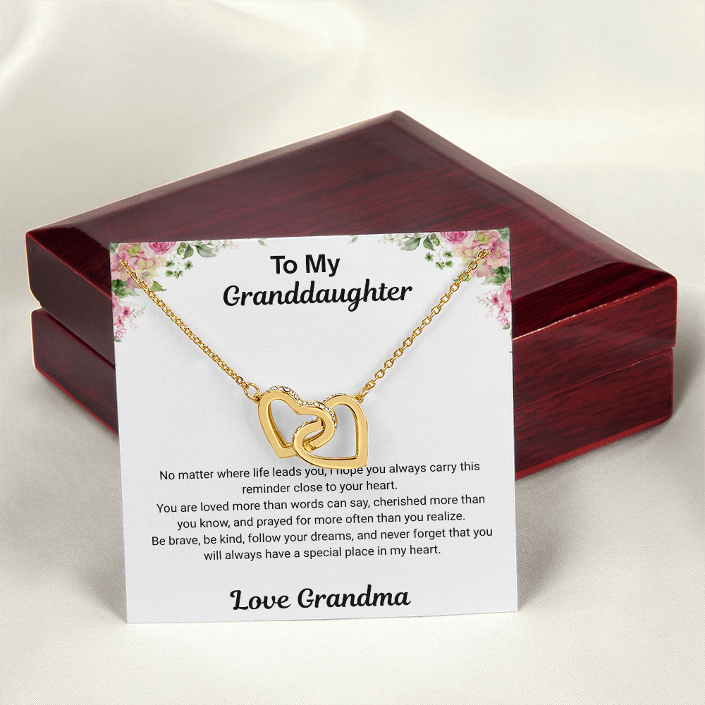 18k yellow gold-finish Interlocking Hearts Necklace displayed with To My Granddaughter message card from Grandma in front of closed mahogany-style luxury box