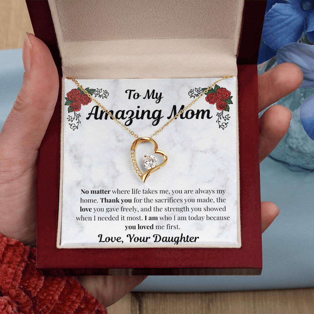 Hand holding 18k yellow gold-finish Forever Love Necklace in mahogany gift box