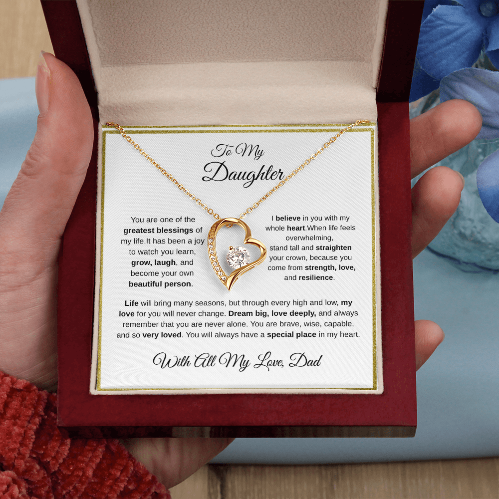 Hand holding 18k yellow gold-finish Forever Love Necklace in mahogany gift box