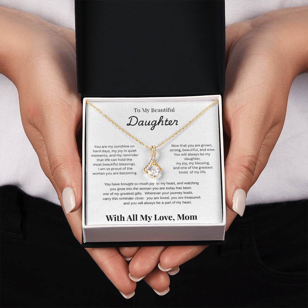 Hands holding 18K yellow gold-finish Alluring Beauty Necklace in standard gift box