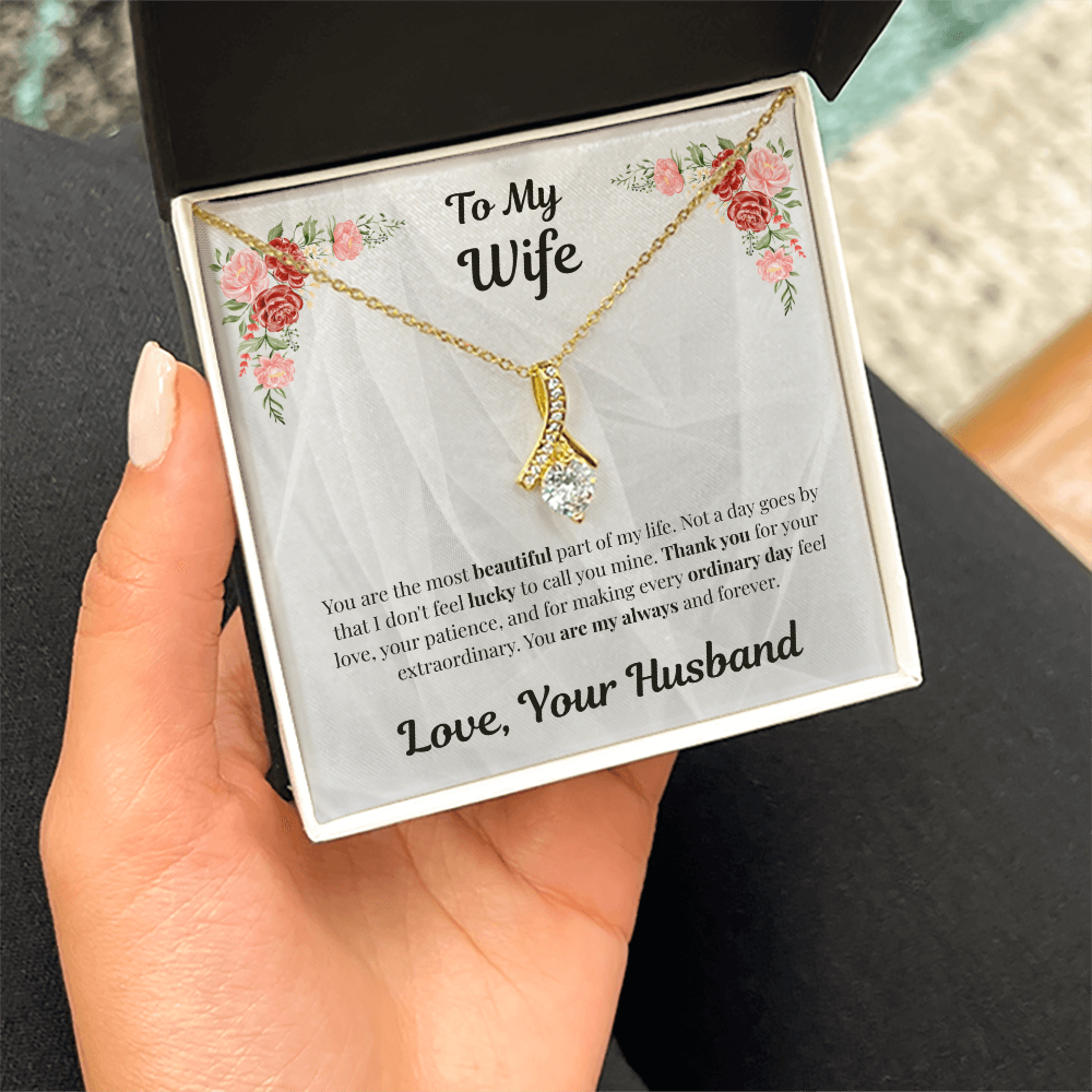 Hand holding 18K yellow gold-finish Alluring Beauty Necklace in standard gift box indoors