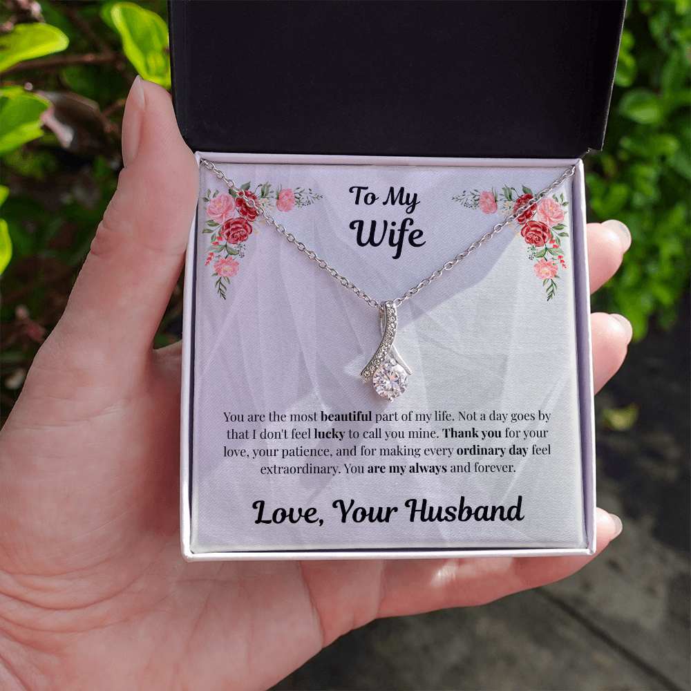 Hand holding 14k white gold-finish Alluring Beauty Necklace in standard gift box outdoors