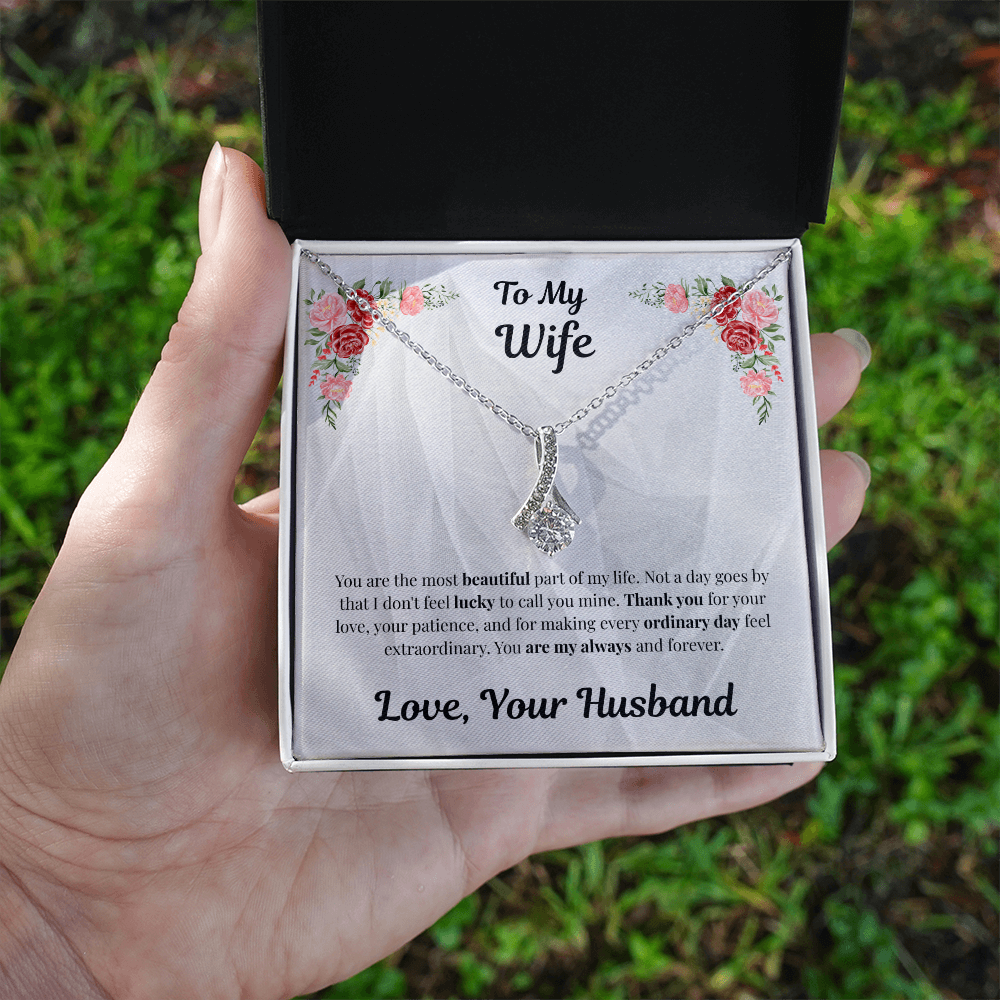 Hand holding 14k white gold-finish Alluring Beauty Necklace in standard gift box over grass