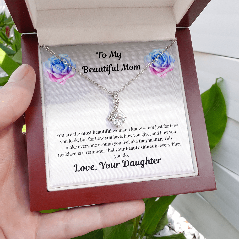 Hand holding 14k white gold-finish Alluring Beauty Necklace in mahogany gift box beside greenery