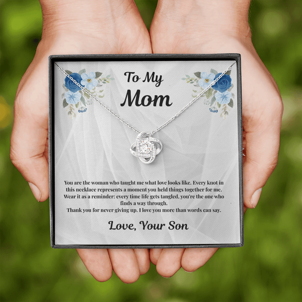 Hands holding 14K white gold-finish Love Knot Necklace and Mom message card