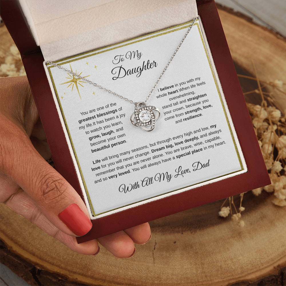 Hand holding 14K white gold-finish Love Knot Necklace in mahogany gift box
