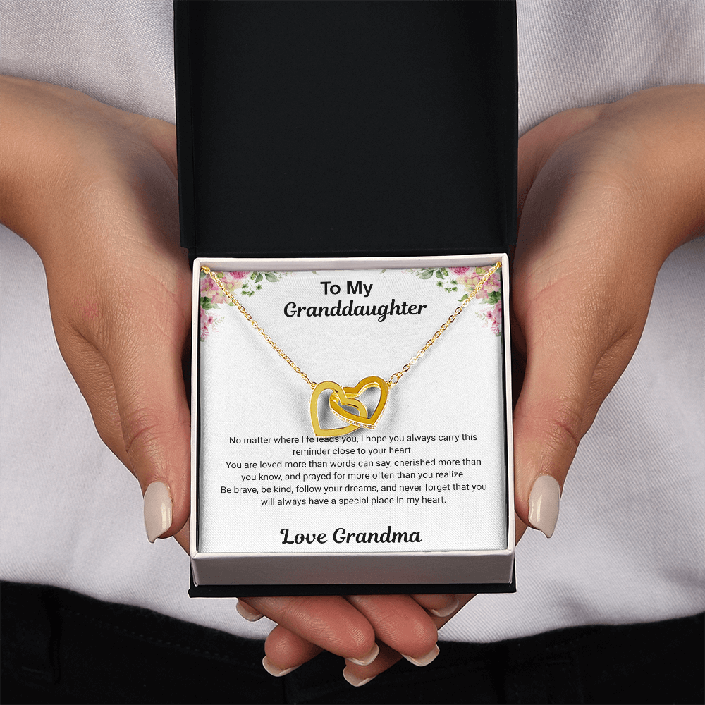 Hands holding 18k yellow gold-finish Interlocking Hearts Necklace in standard gift box with To My Granddaughter message card from Grandma
