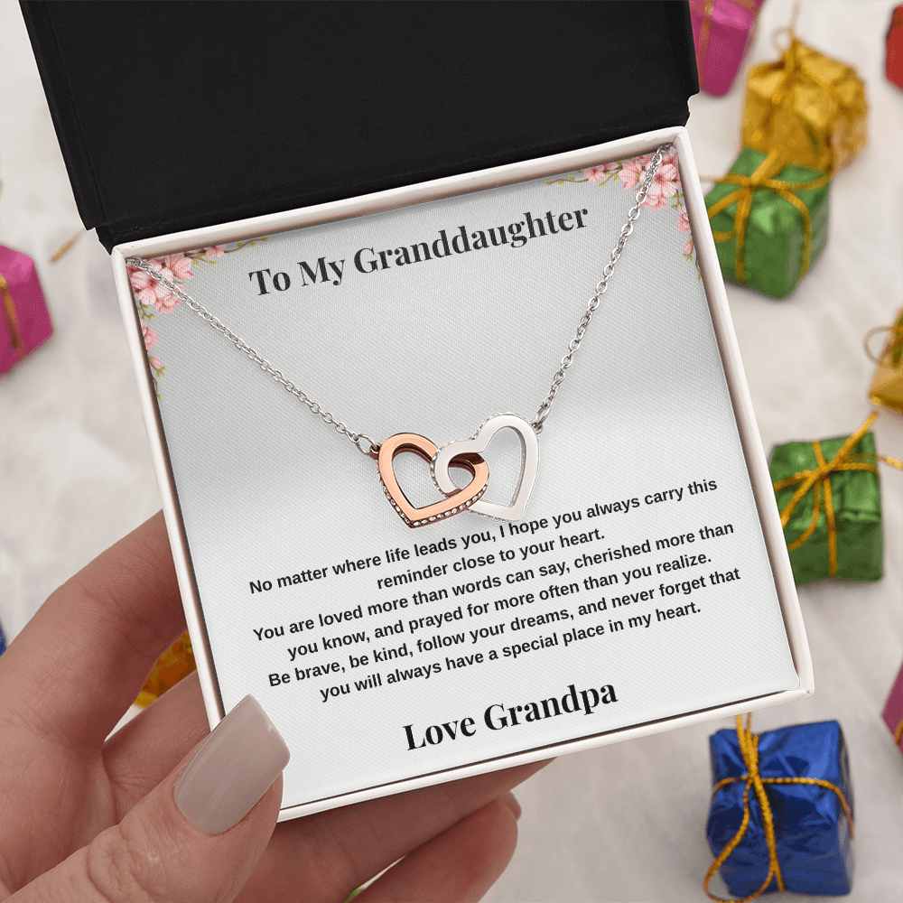 Hand holding 14k white gold-finish Interlocking Hearts Necklace in gift box with Christmas gift boxes in background