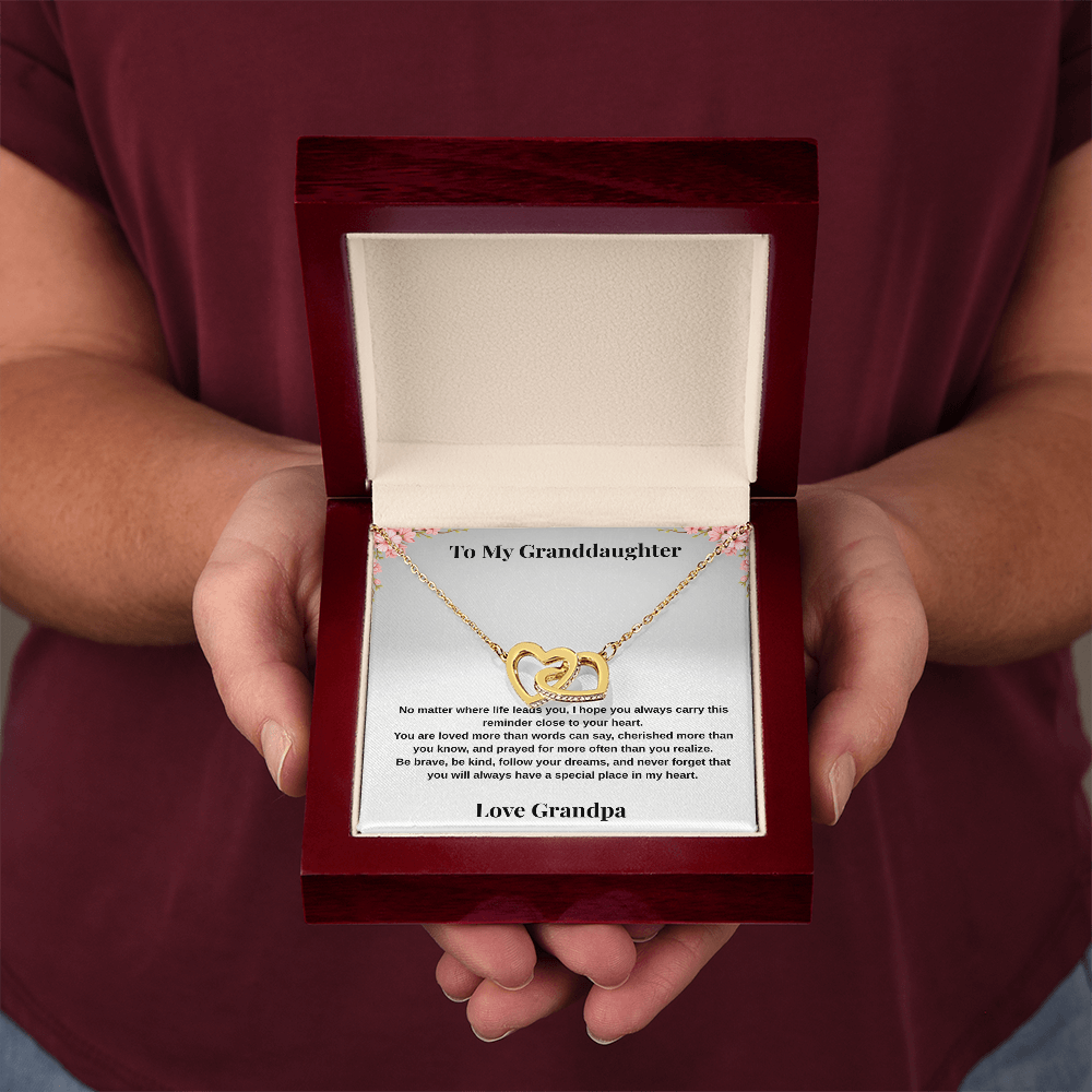 Hands holding 18k yellow gold-finish Interlocking Hearts Necklace in open mahogany-style luxury box with To My Granddaughter message card from Grandpa
