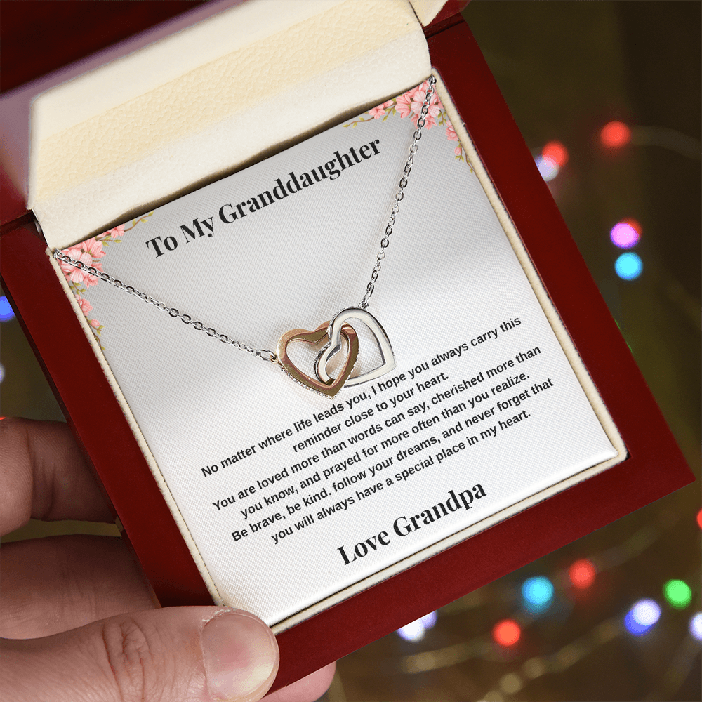 Hand holding 14k white gold-finish Interlocking Hearts Necklace in mahogany-style luxury box with To My Granddaughter message card from Grandpa