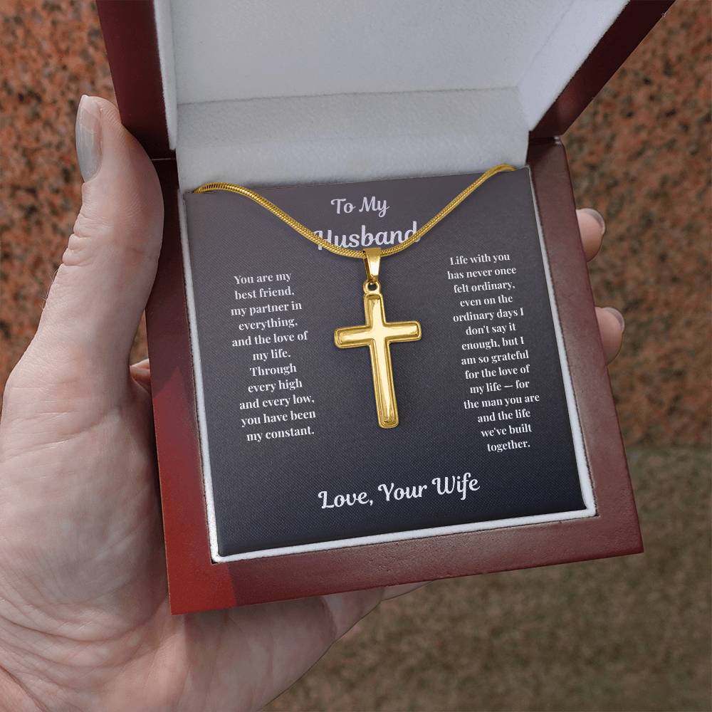 Hand holding gold-finish Cross Necklace in mahogany gift box